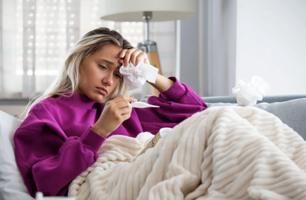 distressed person laying on couch reading thermometer